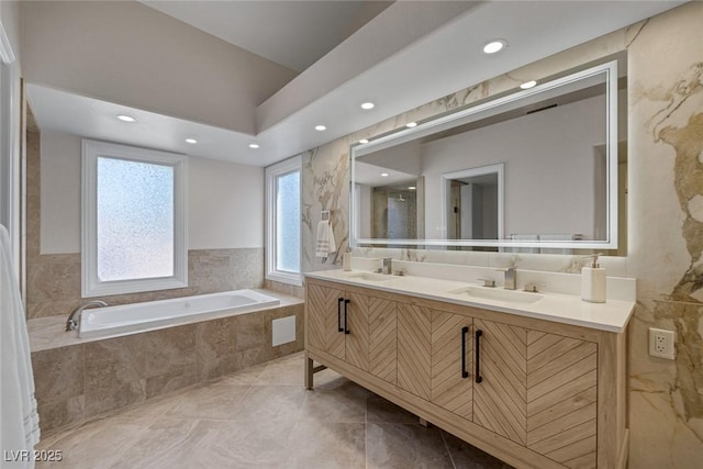 full bath featuring a garden tub, recessed lighting, double vanity, and a sink