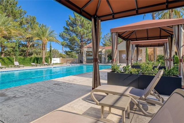 community pool with a gazebo, fence, and a patio