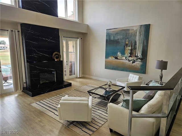 living area featuring a high ceiling, a healthy amount of sunlight, and wood finished floors