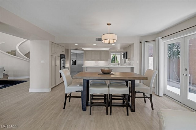 dining area featuring visible vents, light wood-style flooring, french doors, and baseboards