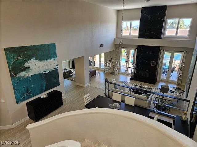 living room with wood finished floors, visible vents, a towering ceiling, and baseboards