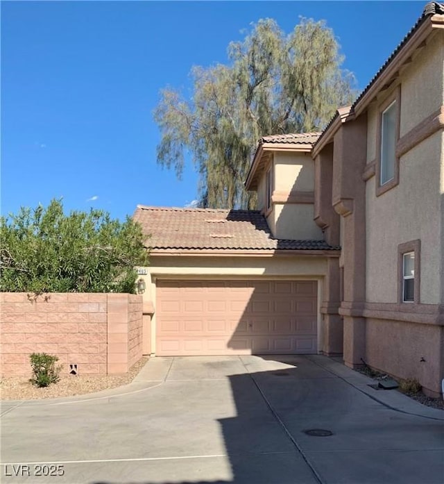 view of front of house with a tile roof, fence, driveway, and stucco siding