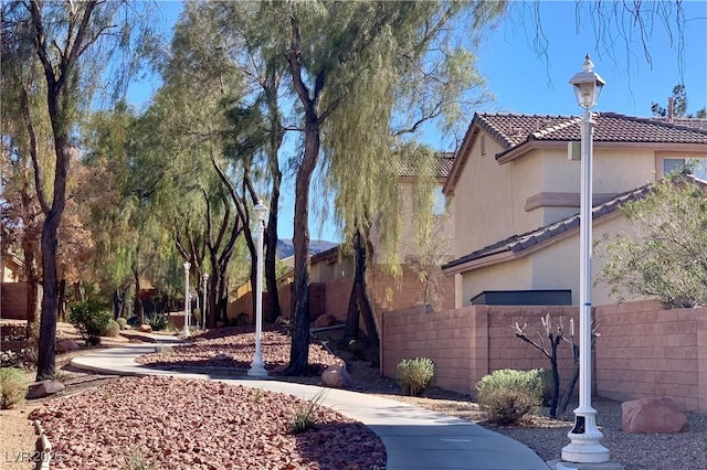 exterior space with a tile roof, fence, and stucco siding