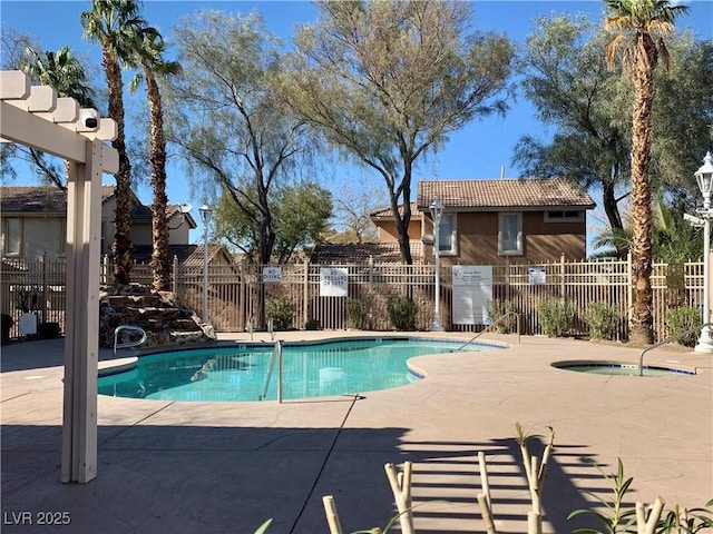 community pool with a hot tub, a patio, and fence