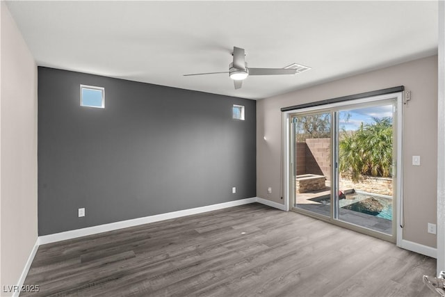 unfurnished room with visible vents, baseboards, wood finished floors, and a ceiling fan