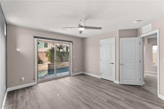 unfurnished bedroom featuring visible vents, access to outside, wood finished floors, and baseboards