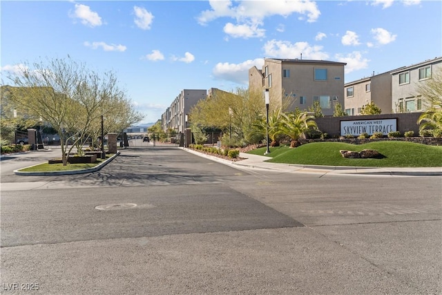 view of street with a gate, a residential view, curbs, and sidewalks