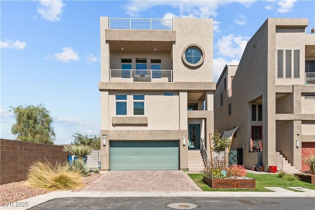 view of front facade with decorative driveway, an attached garage, and stucco siding