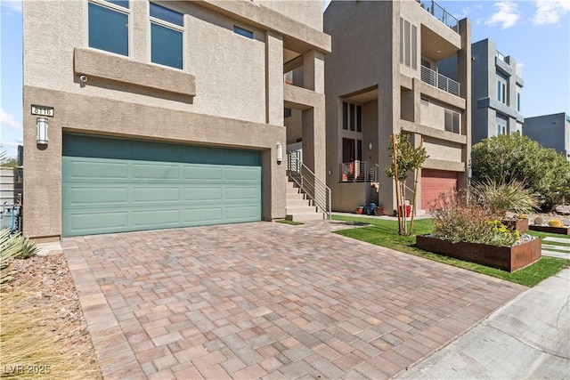 view of front facade with stucco siding, decorative driveway, and a garage