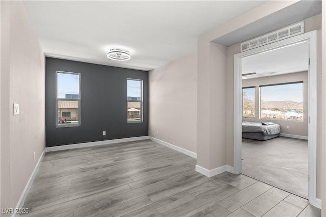 empty room with a wealth of natural light, baseboards, and wood finished floors