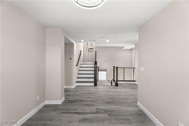 hallway featuring an upstairs landing, baseboards, and wood finished floors