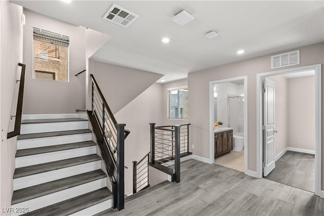 staircase featuring visible vents, recessed lighting, baseboards, and wood finished floors