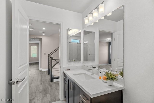 bathroom with visible vents, plenty of natural light, wood finished floors, baseboards, and vanity