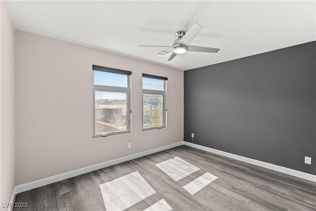 unfurnished room featuring visible vents, baseboards, ceiling fan, and wood finished floors