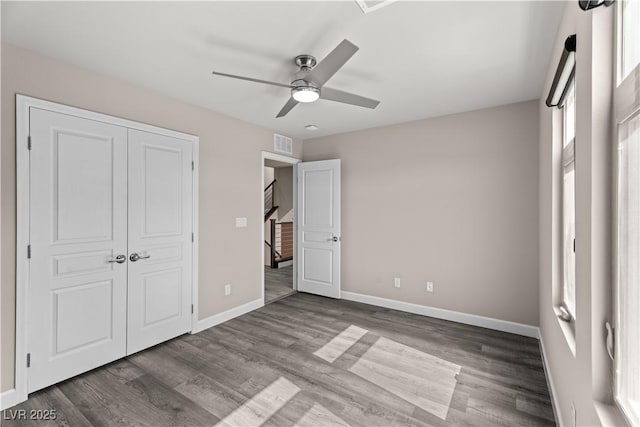 unfurnished bedroom with visible vents, ceiling fan, baseboards, wood finished floors, and a closet