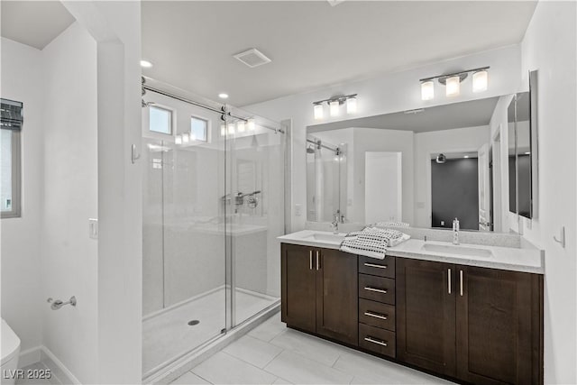 bathroom with a shower stall, double vanity, visible vents, and a sink