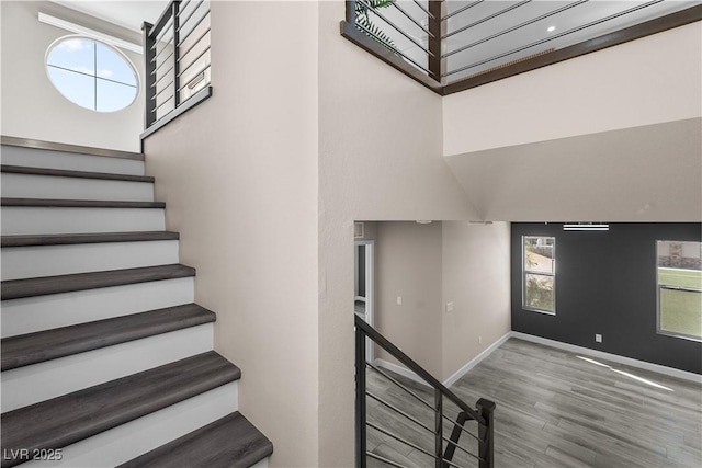 stairway featuring wood finished floors, baseboards, and a wealth of natural light