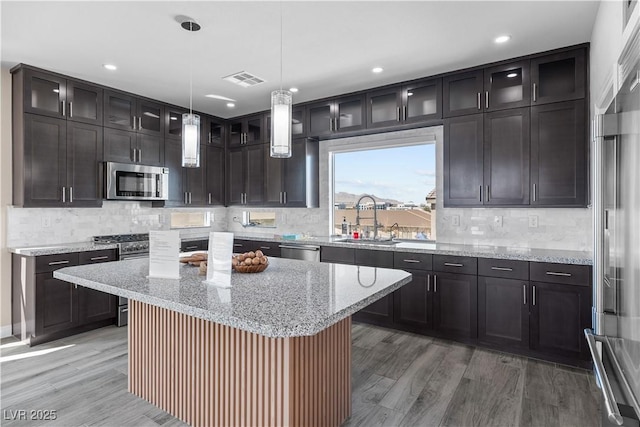 kitchen with a sink, premium appliances, visible vents, and light wood-style flooring