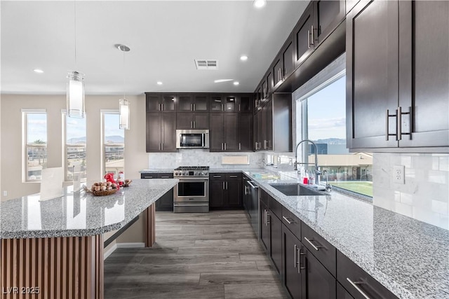 kitchen featuring light stone countertops, visible vents, a sink, decorative backsplash, and stainless steel appliances