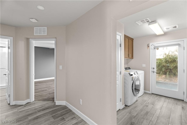 clothes washing area with light wood finished floors, visible vents, cabinet space, and washing machine and clothes dryer