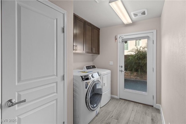 laundry area with visible vents, baseboards, light wood-style flooring, cabinet space, and separate washer and dryer