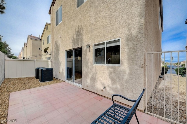 rear view of property with a patio area, stucco siding, cooling unit, and a fenced backyard