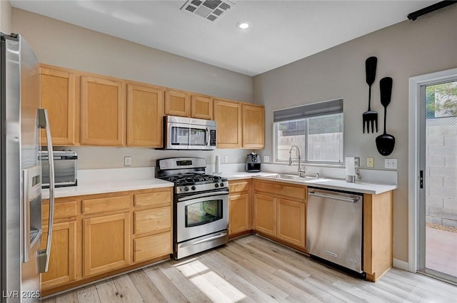 11092 Abbeyfield Rose Dr, Henderson, NV 89052 - kitchen with a sink, stainless steel appliances, light brown cabinets, light wood-type flooring, and visible vents