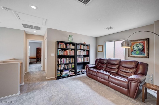 living room with visible vents, carpet flooring, and attic access