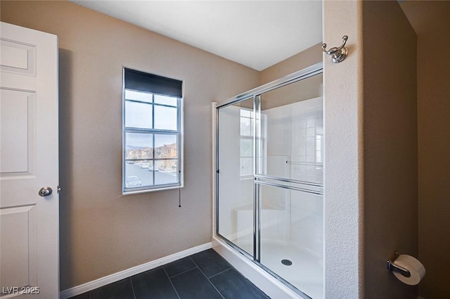 full bath featuring tile patterned flooring, a shower stall, and baseboards