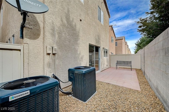 exterior space featuring central AC unit, a fenced backyard, and stucco siding