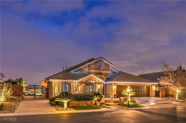 view of front of home with stucco siding, a gate, fence, concrete driveway, and a garage