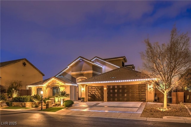 mediterranean / spanish house with stucco siding, driveway, an attached garage, and a tile roof