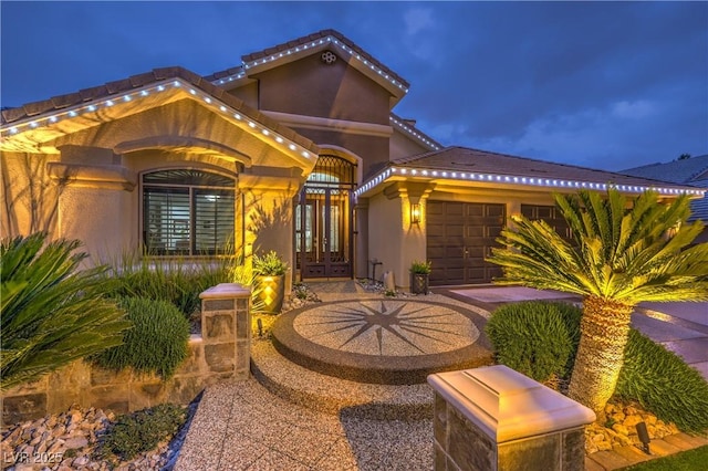 exterior space with a tiled roof, french doors, an attached garage, and stucco siding