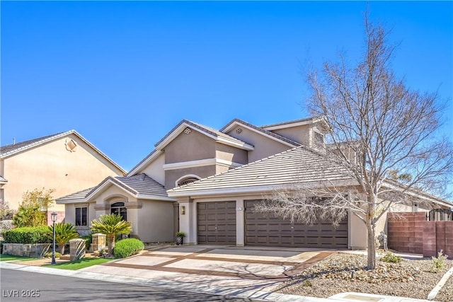 view of front facade with stucco siding, driveway, an attached garage, and fence