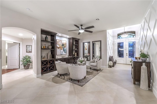 living room featuring a ceiling fan, visible vents, arched walkways, and baseboards