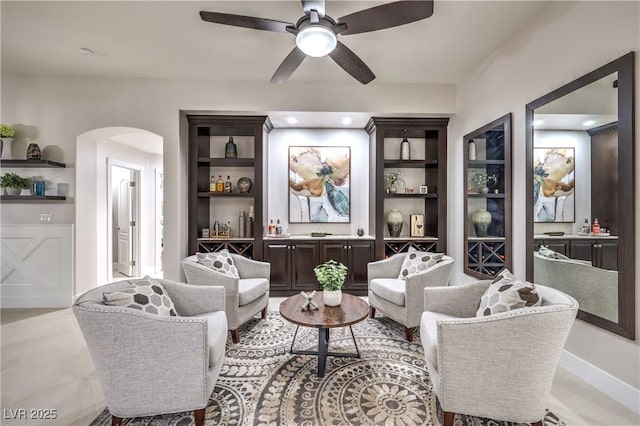 sitting room featuring arched walkways and ceiling fan