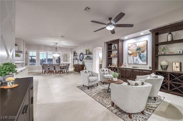 living area featuring recessed lighting, visible vents, arched walkways, and a ceiling fan