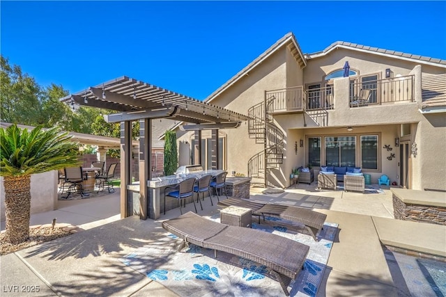 rear view of house featuring stucco siding, a pergola, a patio, an outdoor hangout area, and a balcony