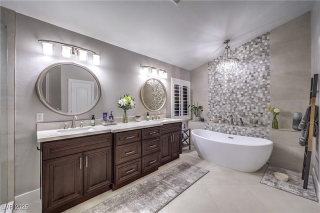 bathroom featuring double vanity, a soaking tub, an inviting chandelier, and a sink