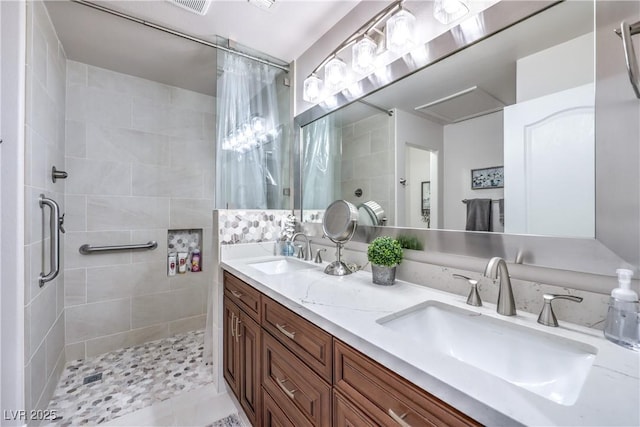 full bathroom featuring double vanity, tiled shower, and a sink