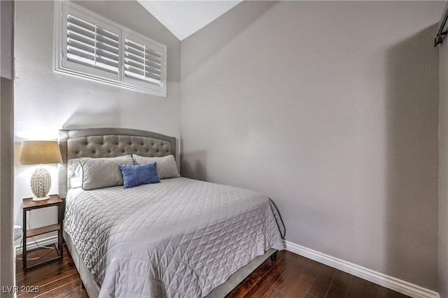 bedroom featuring lofted ceiling, baseboards, and wood finished floors