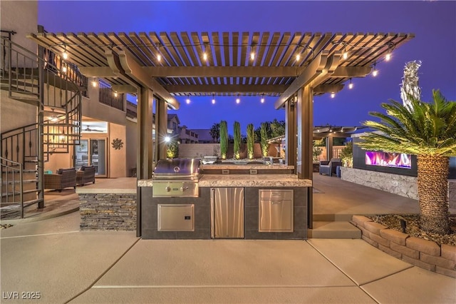 patio at night with grilling area, a pergola, fence, and area for grilling