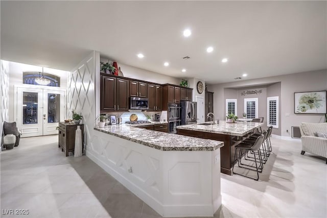 kitchen with a sink, recessed lighting, stainless steel appliances, a breakfast bar area, and dark brown cabinets