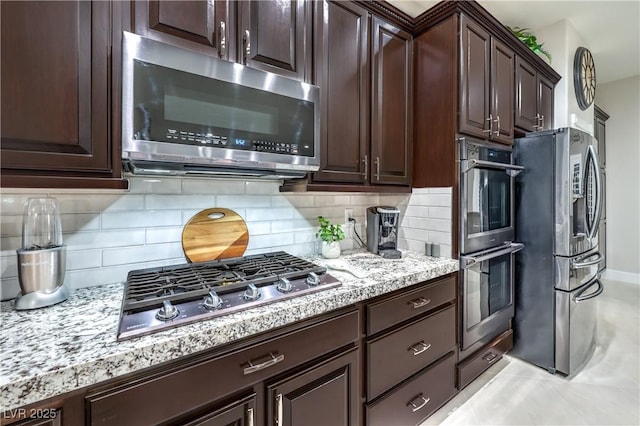 kitchen featuring light stone counters, stainless steel appliances, tasteful backsplash, and dark brown cabinetry