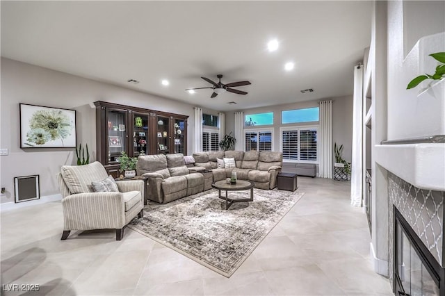 living area featuring a glass covered fireplace, recessed lighting, visible vents, and ceiling fan