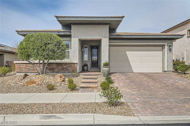 prairie-style house featuring decorative driveway, an attached garage, and stucco siding