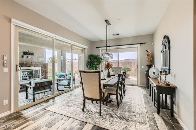 dining room featuring visible vents, baseboards, wood finished floors, and a chandelier