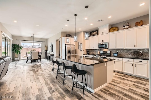 kitchen featuring visible vents, a sink, appliances with stainless steel finishes, dark countertops, and backsplash