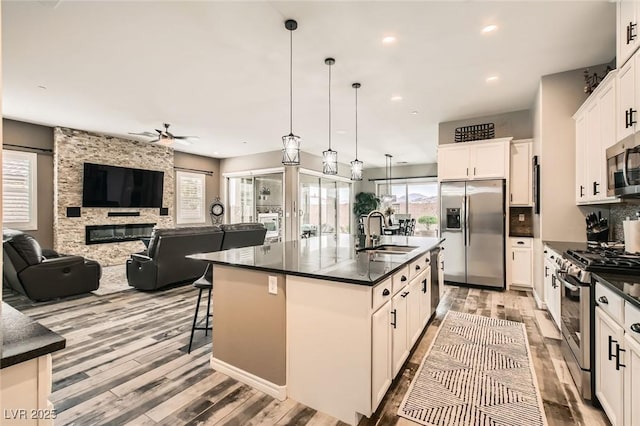 kitchen featuring dark countertops, stainless steel appliances, a ceiling fan, and a sink