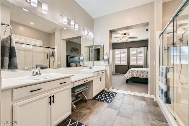 ensuite bathroom with double vanity, a ceiling fan, a stall shower, and a sink